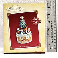 Boxed Hallmark Keepsake Ornament called 'Toyland Treasures' with a Christmas tree and toy figures on a music box base. Box shows minor shelf wear.
