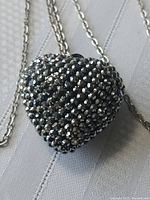 Close-up of heart-shaped pendant on silver-tone chain showing faceted diamond-like finish