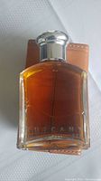 Brown glass bottle of Tuscany Eau de Toilette with silver cap.