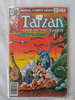 Front cover of Tarzan Lord of the Jungle issue #22 comic book by Marvel Comics Group showing Tarzan fighting prehistoric creatures with a sunset background.