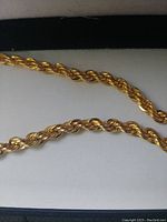 Close-up image of the gold tone rope chain showing its twisted rope pattern and high polished finish.