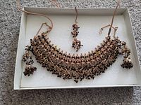 Vintage Indian costume jewelry set including necklace, headpiece, and earrings with dark stones in handcrafted metalwork.