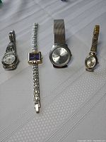 Four ladies watches on a white cloth background showing different face shapes and metal bands.