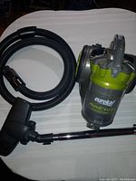 Image of Eureka Airexcel Compact vacuum with hose, wand, and nozzle attachment laid on a white surface