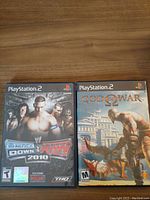 Front covers of SmackDown vs. RAW 2010 and God of War PlayStation 2 games showing artwork, titles, and PlayStation 2 logos.