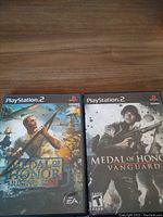 Photo of both Medal of Honor Rising Sun and Medal of Honor Vanguard PS2 game cases side by side on a wooden surface.