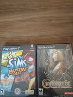 Front cover of The Sims Bustin' Out and Castlevania: Lament of Innocence PlayStation 2 games showing cover artwork and labeling.