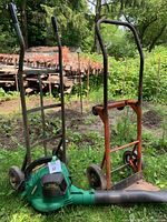 Photo showing Weed Eater Blower/Vac and two metal two-wheel dolly carts outdoors on grass.