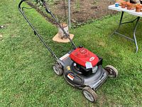Full view of mower on grass showing deck, wheels, handle