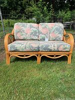 Front view of rattan loveseat showing floral cushioned seating and backrest.