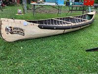 Full side view of canoe on grass showing hull shape, foam gunwale padding and overall condition.