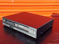 Black Optimus CD-1750 CD player showing top and front with control buttons and a digital display.