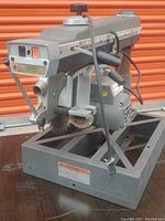 Side view of the Black and Decker commercial wood saw on metal base, showing motor, power cord, and saw arm with measuring guide.