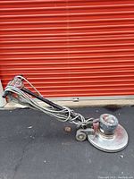 Side view of the Thoro-Matic floor buffer showing the handle, wheels, power cord, and metal base plate.