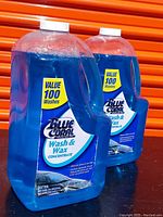 Two plastic jugs of Blue Coral Wash & Wax Concentrate with visible front labels showing product details and blue liquid inside.