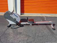 Full side view of the rower showing the full length, seat, rail, and flywheel housing in front.