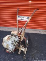 Front view of a Winston Model GM710 gasoline tiller/cultivator showing the engine, handles with grips, wheels, and cultivating blades.