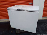 Front view of white Kenmore chest freezer showing wear and dirt on top and front surfaces.