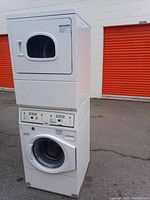 Front view of white UniMac stacked washer and dryer unit with both doors closed and control panel visible.