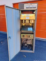 Full height metal rack cabinet with open door showing mounted electronic components and wiring inside, GE Master 2 mobile radio station center.