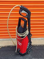 Full view of Husky pressure washer with hose neatly wrapped and spray gun attached, showcasing the unit's upright design and wheels.