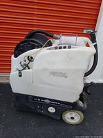 Left side view of machine showing white solution tank, black base, hose reel and wheels