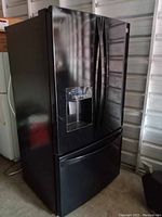 Front view of black refrigerator with French doors and bottom freezer drawer