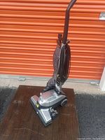 Full view of Kirby G4 heavy duty upright vacuum cleaner showing chrome base, grey cloth bag, brown handle, power cord wrapped around handle, and branding on bag.