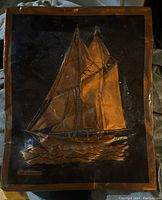 Front view of the antique copper relief artwork featuring the Bluenose ship, showing details and bent damage.