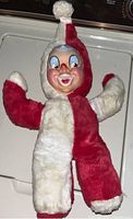Front view of vintage stuffed jester/clown doll with red and white plush body and rubber face.
