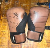 Front view of brown and black Hayabusa boxing gloves, showing the knuckle padding and wrist straps with Velcro closure.