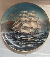 Front of The Great Clipper Ships Collector Plate featuring the clipper ship Challenge in full sail on the ocean under a blue sky with clouds, with gold rim detailing.