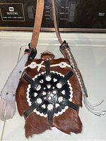 Front view of the vintage water canteen showing brown fur body with black leather design and white accents, leather strap with cut-out patterns.