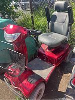 Red Invacare Meteor mobility scooter angled left side showing seat, footrest and front basket