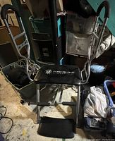 View of full Pilates Pro Chair with metal frame, cushioned seat, foot pedal, and side handles in basement setting.