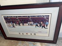 Framed collector print titled 'Senators Showdown' showing a hockey scene inside a stadium with players on ice; dark wooden frame with white mat.