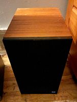 Front top view of one speaker showing wooden cabinet finish and black speaker grille with B&W logo.