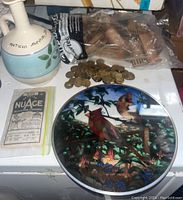 Italian ceramic vase with light blue band and olive decoration, marked 'Patichi Sapori', alongside stained glass panel featuring birds and botanical artwork. Also included a small yellow packet labeled 'Nu-Ace' and some coin tokens.