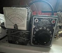 Full view of Heathkit voltmeter and Variac autotransformer side by side on flat surface in natural light, showing front and side of devices.