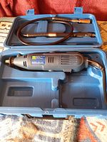 Rotary tool and flexible shaft in blue case, top view showcasing rotary tool body and flexible shaft coiled in upper compartment.