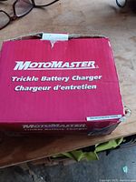 Closed red MotoMaster box labeled 'Trickle Battery Charger Chargeur d'entretien'.