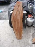 Side view of wooden slab showing smooth polished surface with natural wood grain and shape.