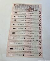Photo of ten 1986 Canadian $2 bills with sequential serial numbers from EGT3988428 to EGT3988437 showing front side with Queen Elizabeth II portrait.