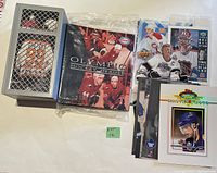 Overview of hockey memorabilia lot laid out on a surface, showing trading cards, photos, and sealed card pack in plastic wrap