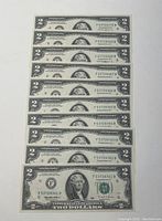 Set of ten $2 bills arranged in a line showing sequential serial numbers and front side detail.