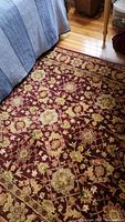 Photo showing the plush red floral patterned area rug near hardwood floor and furniture.