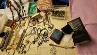 Wide view of the lot showing necklaces, bracelets, wallet, compact, and jewerly items scattered on fabric.
