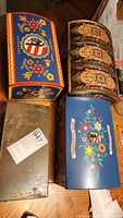 Photo showing the top view of the four items: three vintage German decorative metal tins with attached lids and latch closures, and one locking metal storage box with key.