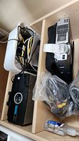 Photo showing the Epson PowerLite projector and Sawyers projector along with assorted cords in a plastic container