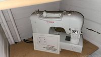 Front view of white Singer 2550 sewing machine with instruction manual placed in front